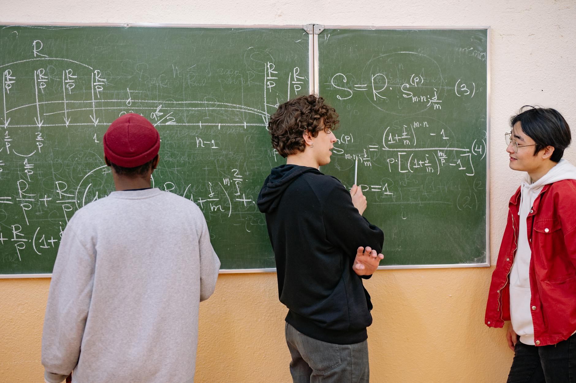 Uczniowie wspólnie rozwiązują zadania matematyczne przy tablicy w klasie