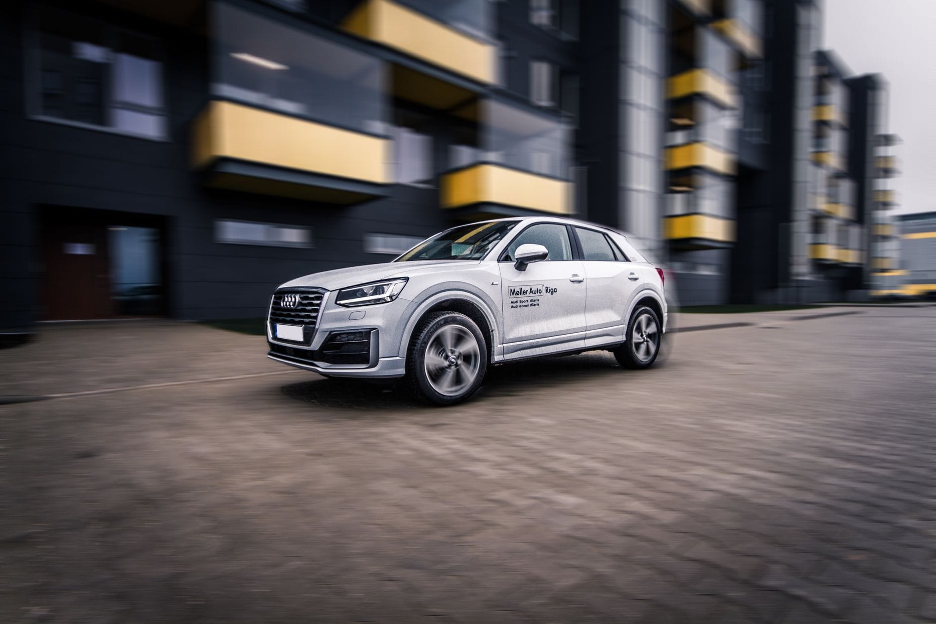 Srebrne Audi SUV jadące szybko ulicą nowoczesnego miasta